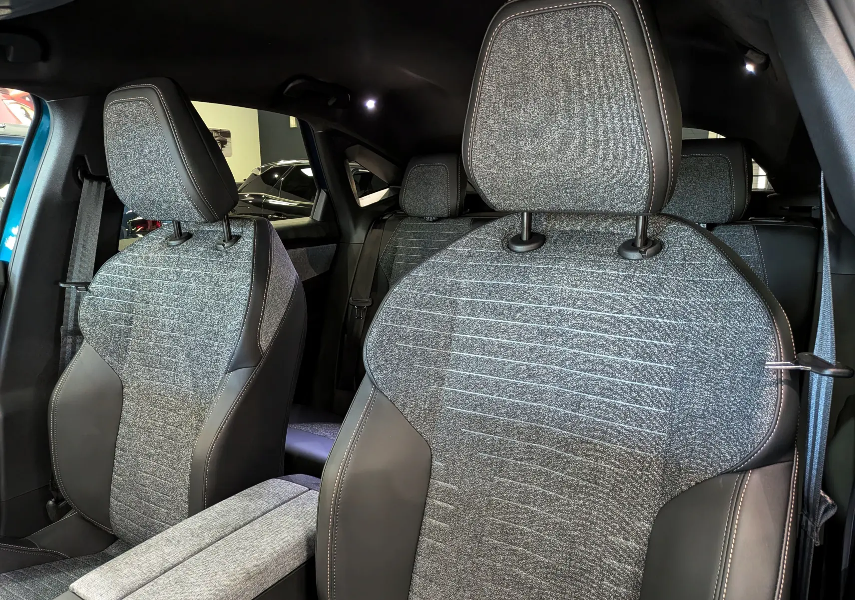 Vue intérieure rapprochée des sièges avant en tissu gris et cuir noir du Peugeot 3008 Hybrid 145 CH e-DCS6 Allure 2026.