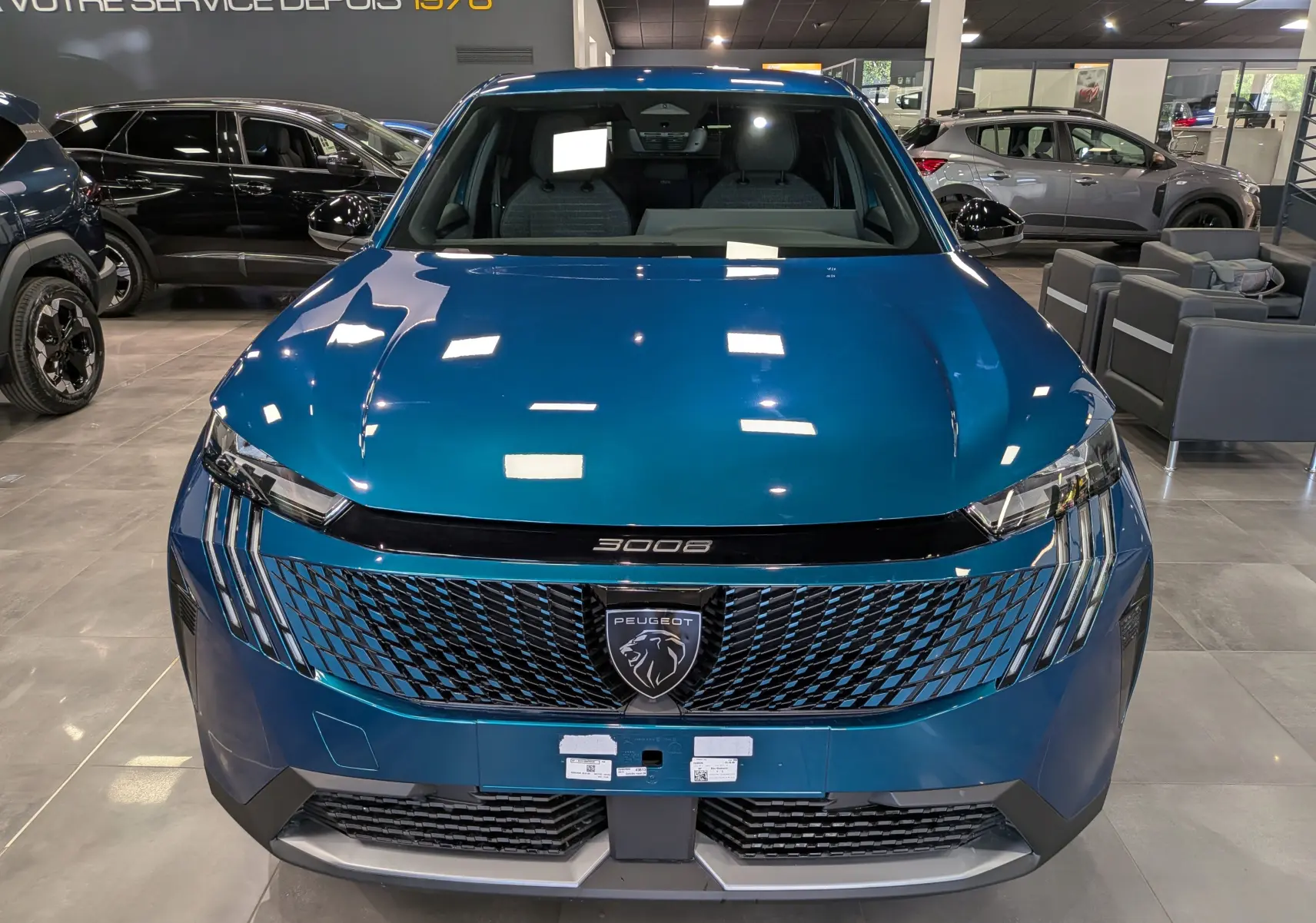 Vue avant d'un Peugeot 3008 Hybrid bleu Obsession avec calandre distinctive et logo lion central en showroom.