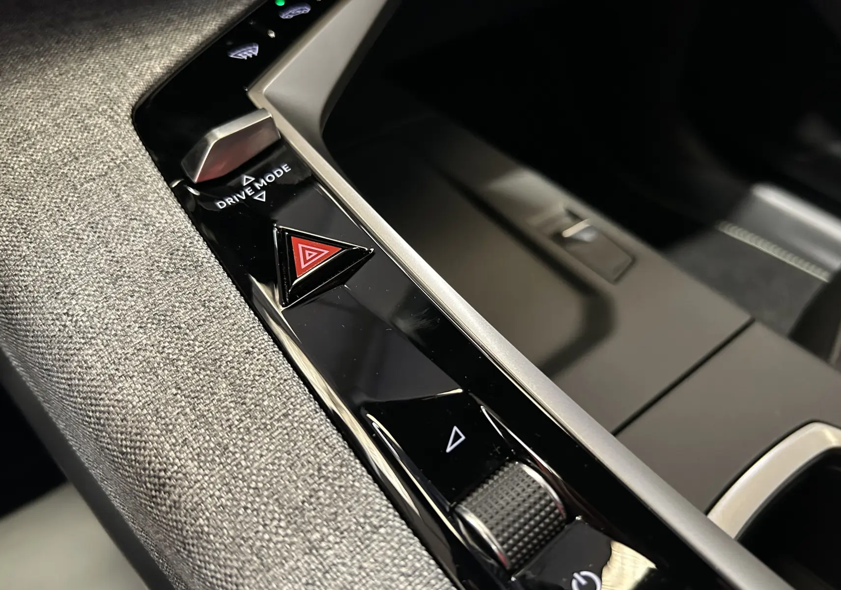 Gros plan sur la console centrale noire brillante du Peugeot 3008 Hybrid blanc, avec bouton triangle rouge de warning et molette Drive Mode.