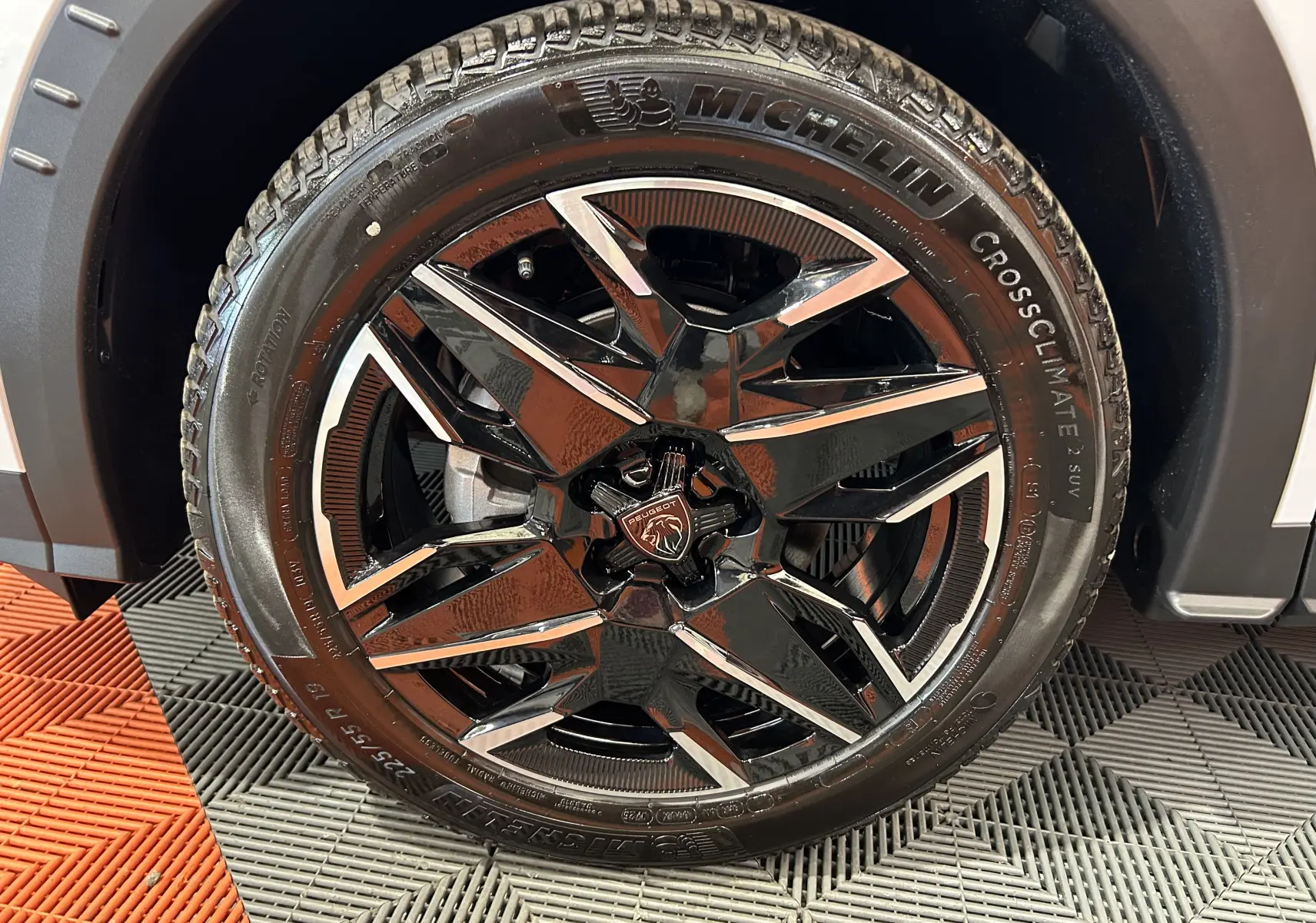 Gros plan sur la roue avant droite du Peugeot 3008 Hybrid blanc, jante alliage noire et chrome avec pneu Michelin CrossClimate.