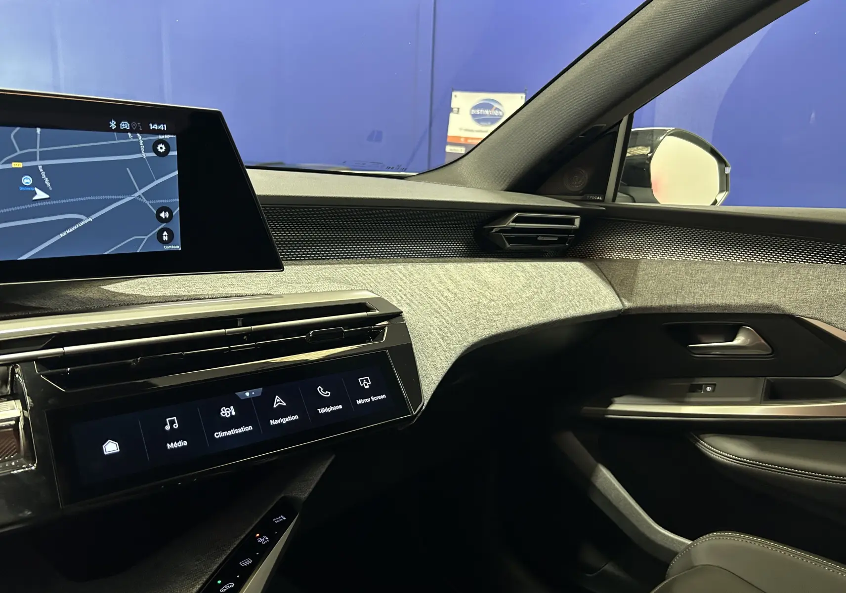 Vue intérieure côté passager du tableau de bord et de la porte d’une Peugeot 3008 III Hybrid blanc Okenite avec écran tactile et finitions tissu gris.