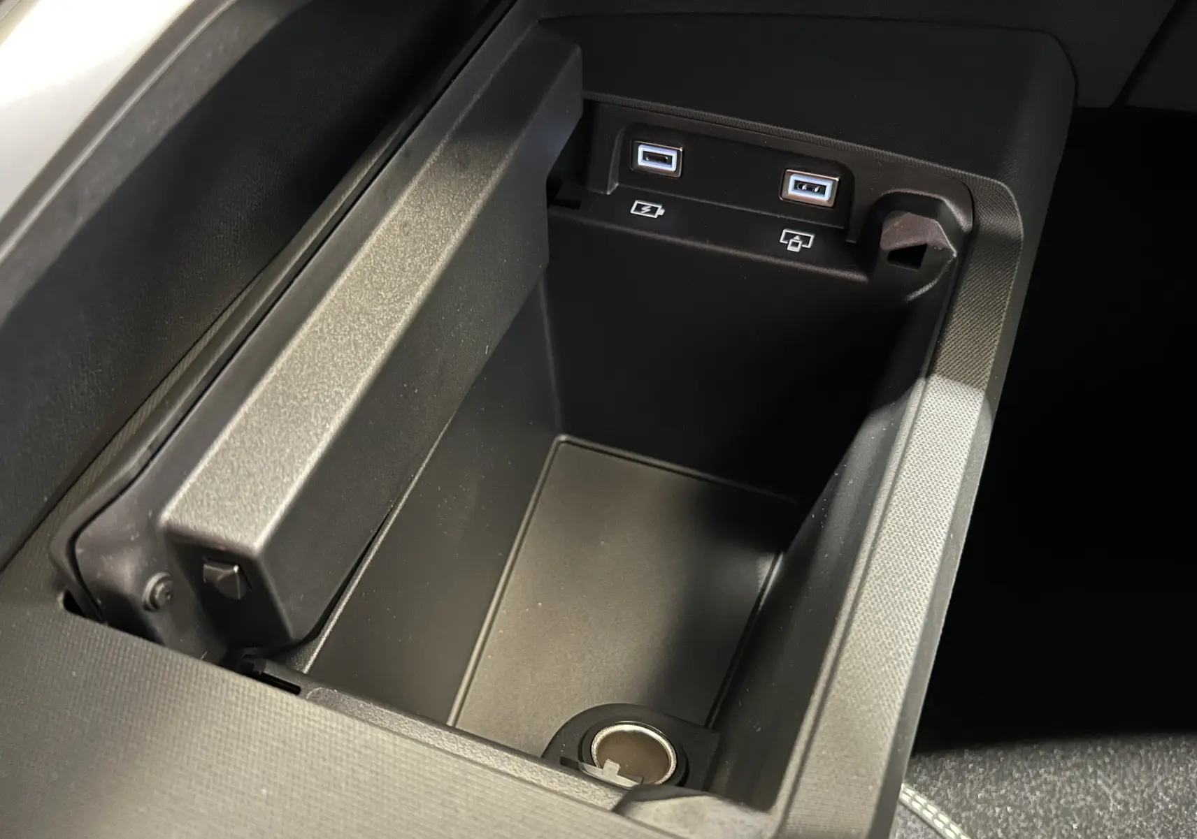 Vue rapprochée de la console centrale noire du Peugeot 3008 Hybrid avec ports USB et prise 12V intégrés.