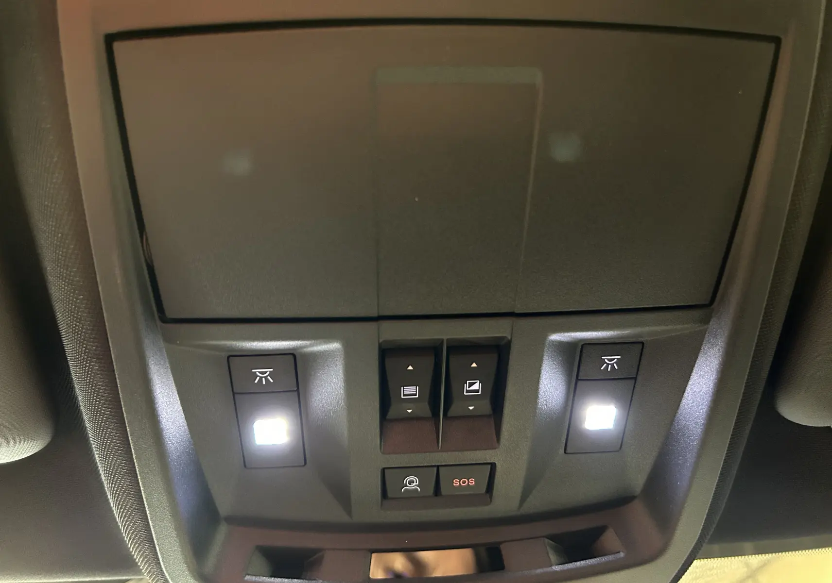 Vue en gros plan du plafonnier intérieur du Peugeot 3008 blanc, avec boutons d’éclairage et alerte SOS éclairés.