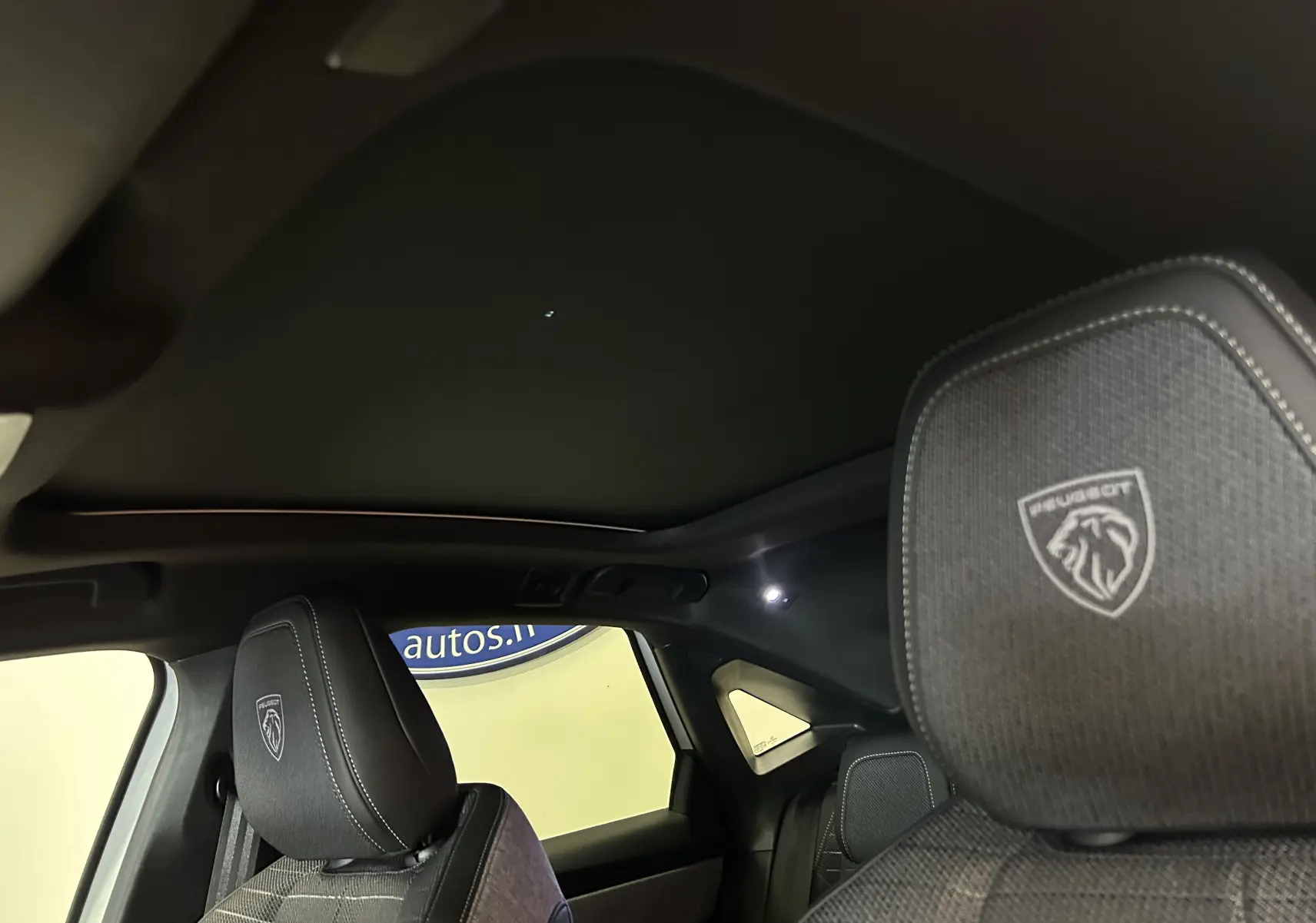 Vue intérieure du toit ouvrant panoramique et des appuie-têtes avant brodés Peugeot du 3008 blanc Okenite.