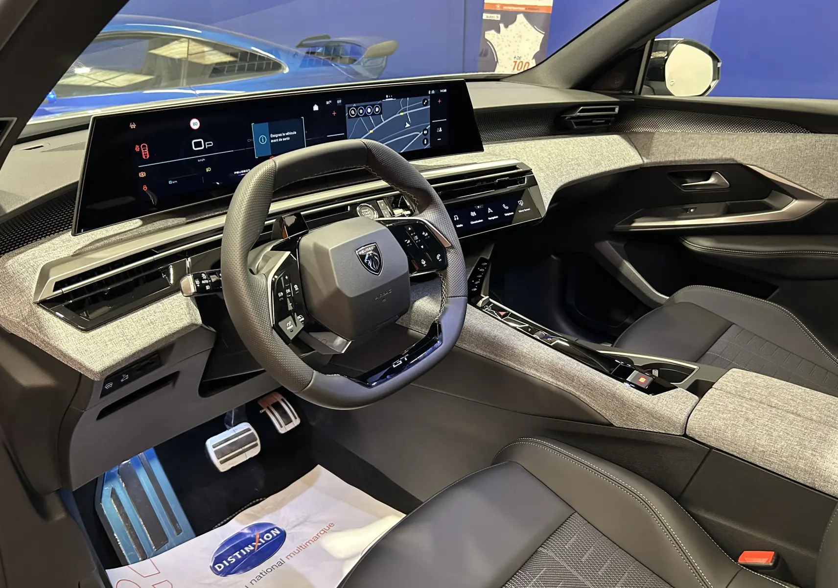 Vue intérieure côté conducteur du Peugeot 3008 Hybrid 2026, tableau de bord moderne avec écran large et sellerie noire et grise.
