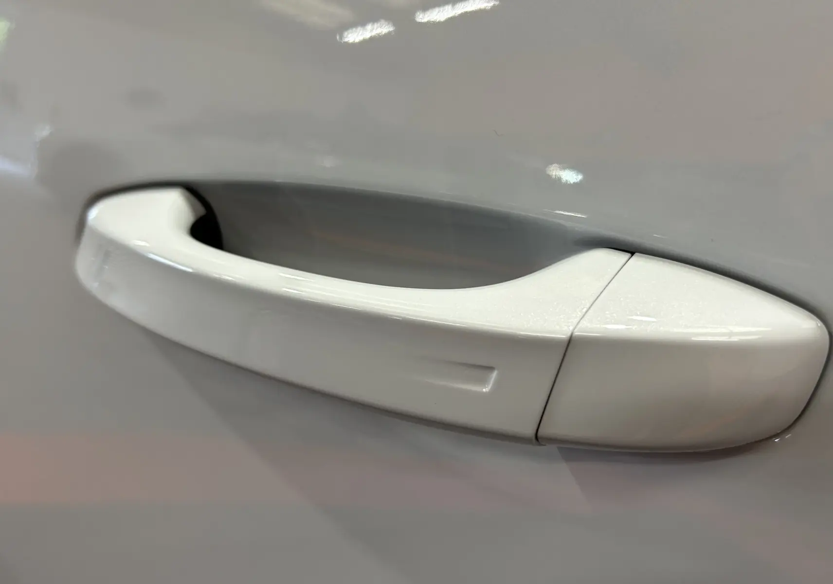 Poignée de porte blanche Okenite en gros plan côté droit du Peugeot 3008 III Hybrid 145ch e-DCS6 GT suréquipé.