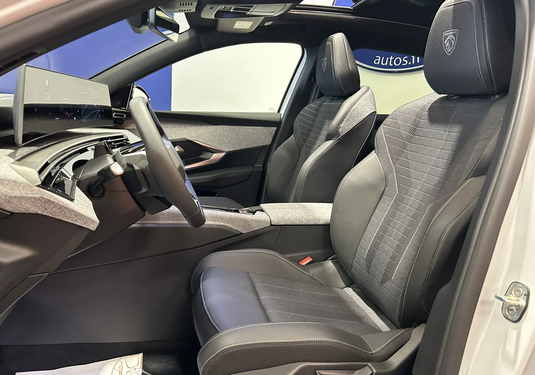 Vue intérieure côté conducteur du Peugeot 3008 Hybrid blanc Okenite, sièges cuir et tissu avec logo Peugeot brodé.