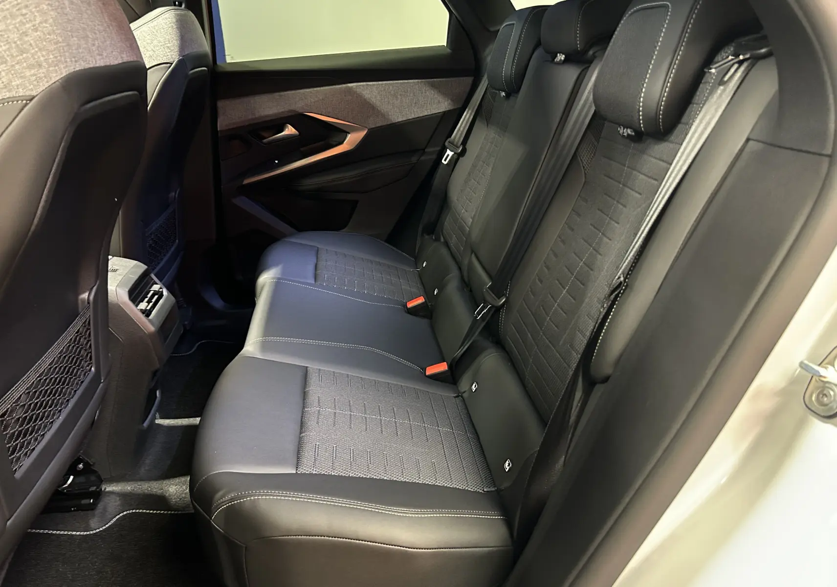 Vue intérieure côté droit des sièges arrière en cuir noir et tissu gris du Peugeot 3008 III Hybrid 145ch blanc Okenite.