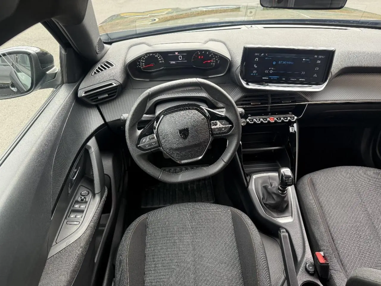 Vue intérieure frontale du Peugeot 2008 2025 noir perla, mettant en valeur le volant compact, la boîte manuelle et l'écran tactile central.