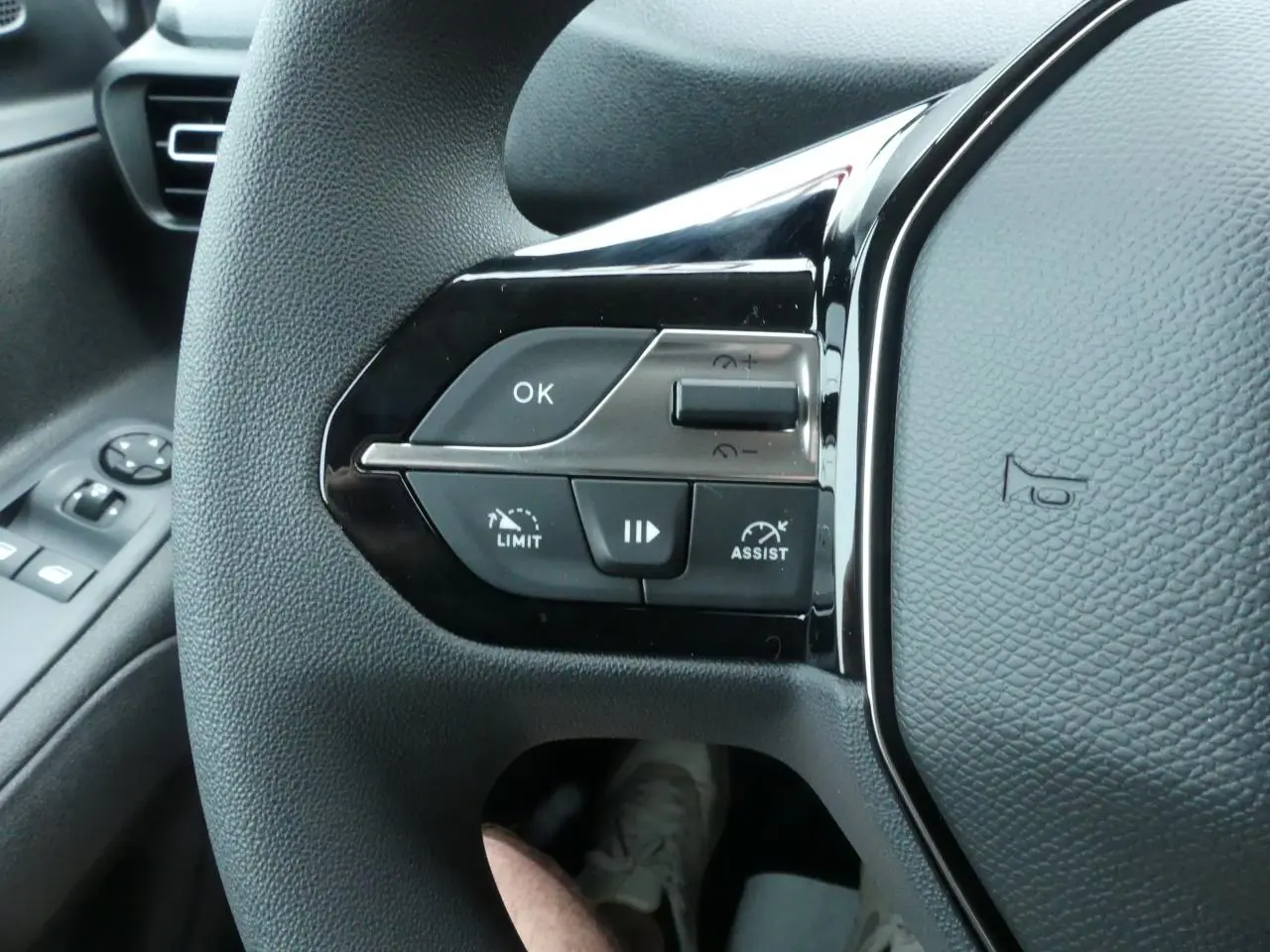 Gros plan sur le volant multifonctions noir du Peugeot Partner 2025 avec commandes de régulateur et limiteur de vitesse.