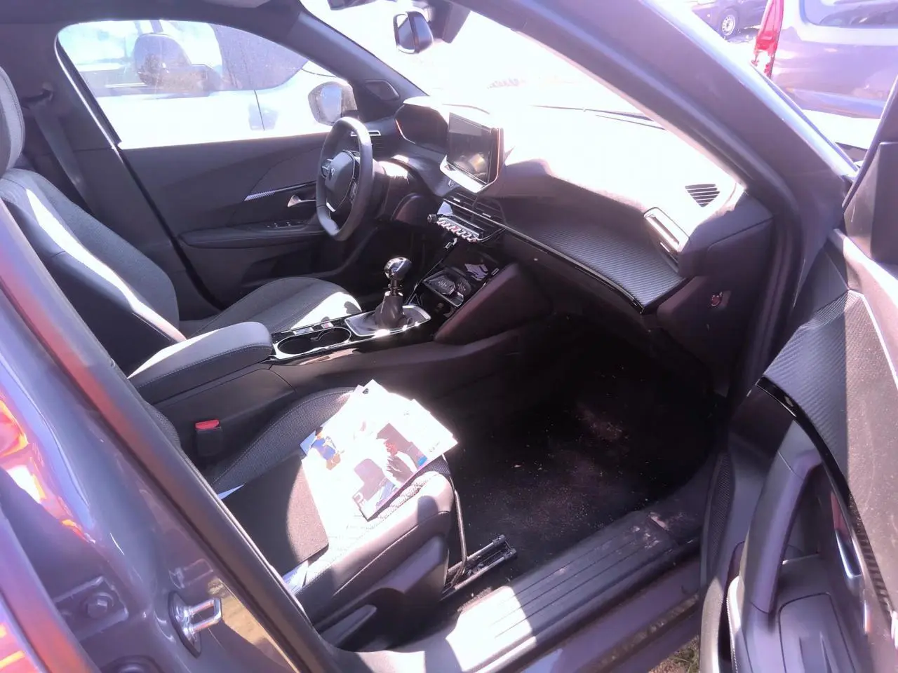 Intérieur avant droit du Peugeot 2008 gris clair 2025, avec tableau de bord carbone et boîte manuelle.