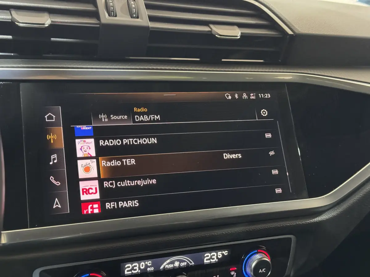 Écran tactile central affichant les stations radio DAB/FM dans l'habitacle noir de l'Audi Q3 35 TFSI 2022.