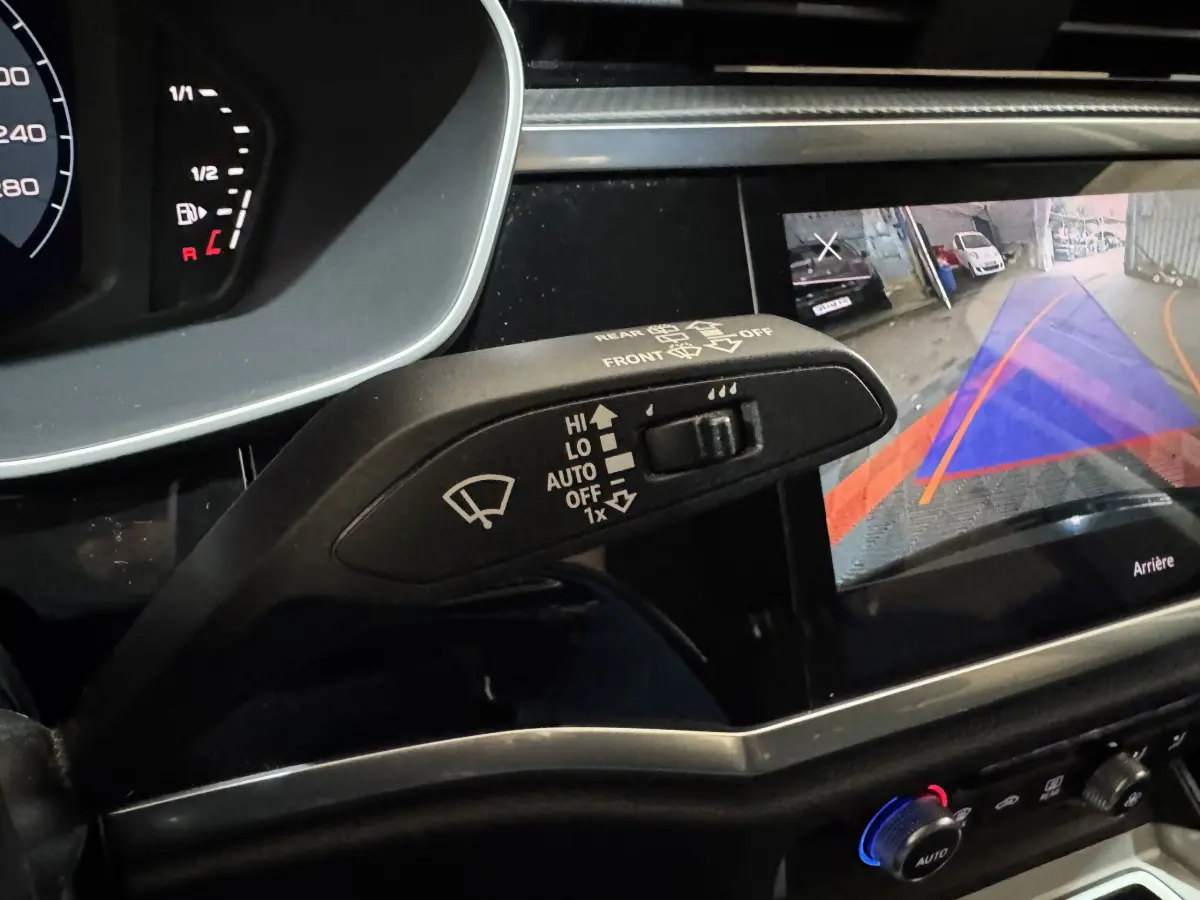 Gros plan sur la commande d’essuie-glace et l’écran de caméra de recul dans l’habitacle noir de l’Audi Q3 2022.