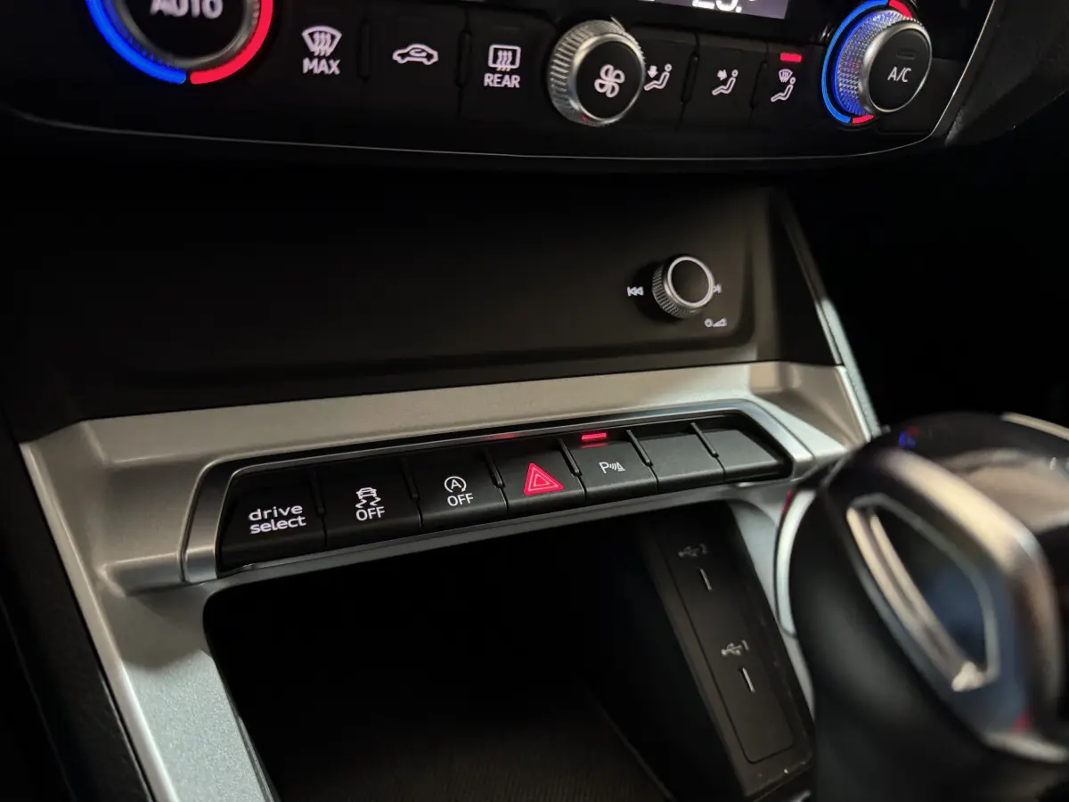 Gros plan sur la console centrale noire de l'Audi Q3 35 TFSI 2022 avec boutons de contrôle et levier de vitesses visible.