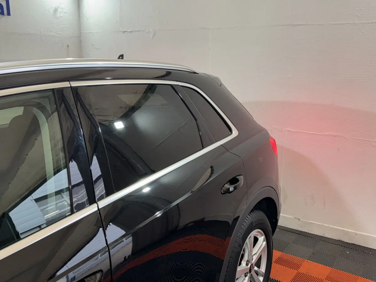 Vue latérale arrière droite d'un Audi Q3 noir brillant avec vitres teintées et jantes alliage argentées.