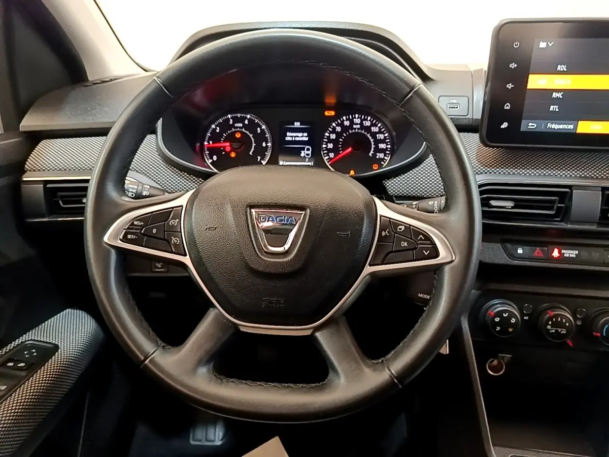 Vue rapprochée du volant noir de la Dacia Sandero 2022 avec tableau de bord et écran tactile visible à droite.