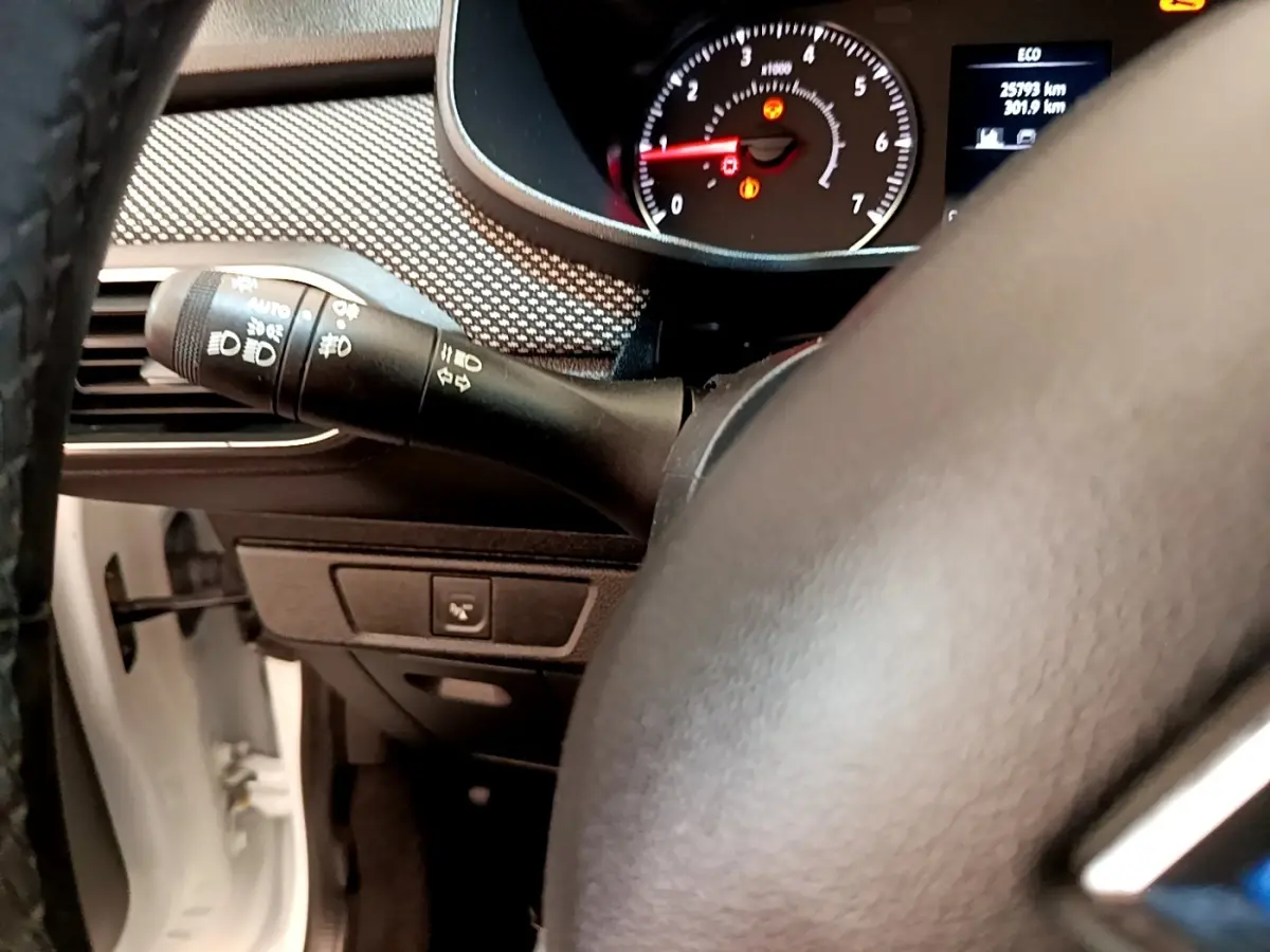 Vue rapprochée du combiné d'instruments et du commodo gauche du tableau de bord d'une Dacia Sandero blanche 2022.