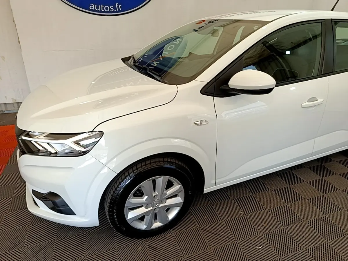 Vue 3/4 avant droit d'une Dacia Sandero blanche 2022 avec phares LED et jantes alliage visibles.
