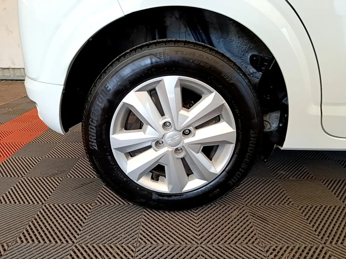 Gros plan sur la roue avant droite d'une Dacia Sandero blanche, mettant en valeur la jante en alliage et le pneu Bridgestone.