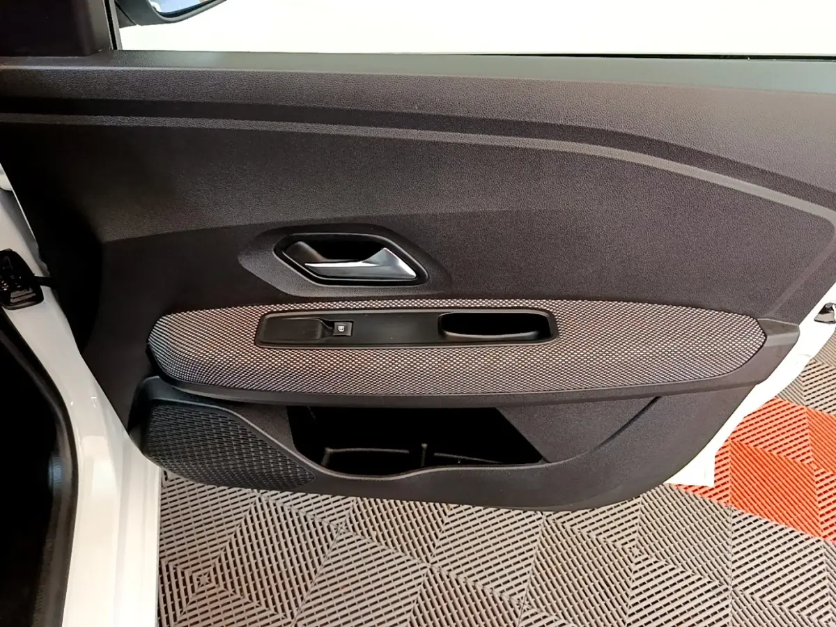 Vue rapprochée de la porte avant gauche blanche d’une Dacia Sandero 2022, avec panneau noir et insert gris texturé.