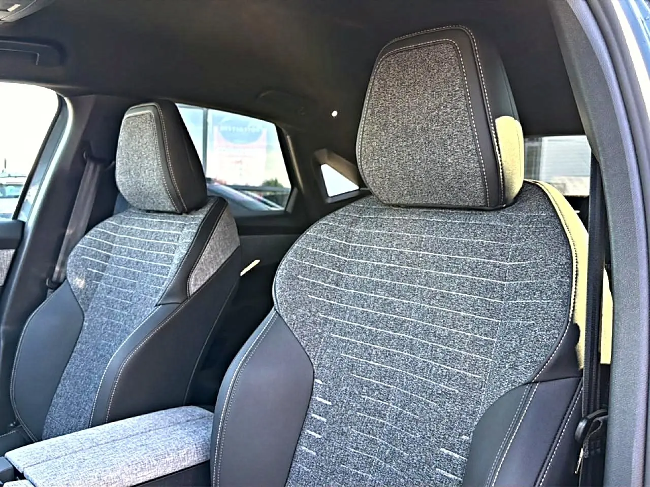 Vue rapprochée des sièges avant en tissu gris et cuir noir du Peugeot 3008 1.2 hybrid 145 allure e-dcs6.