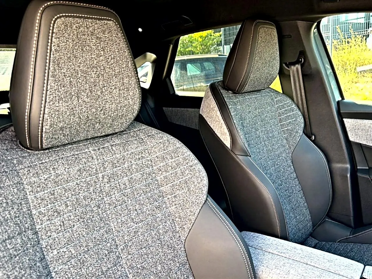 Vue rapprochée des sièges avant en tissu gris et cuir noir du Peugeot 3008 1.2 hybrid 145 allure e-dcs6 2025.