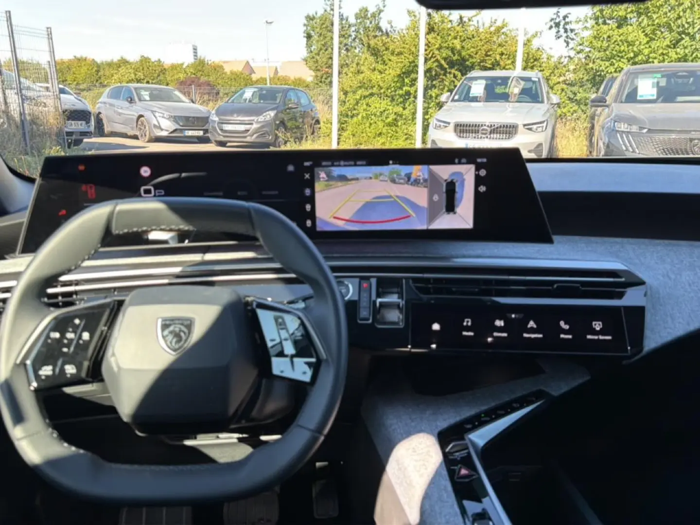 Vue intérieure du tableau de bord du Peugeot 3008 bleu 2025 avec écran tactile et caméra de recul affichée.