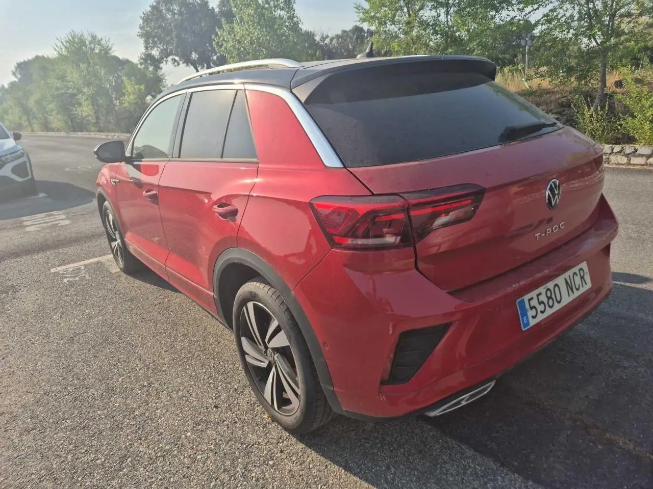 Vue 3/4 arrière droite d'un Volkswagen T-Roc rouge métal foncé avec toit noir et jantes alliage noires.