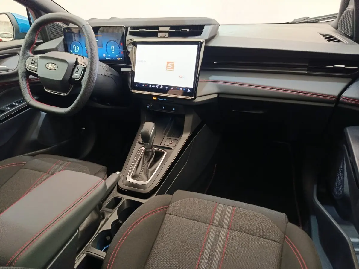Intérieur avant du Ford Puma 2025 ST-LINE, tableau de bord noir avec coutures rouges et écran tactile central lumineux.
