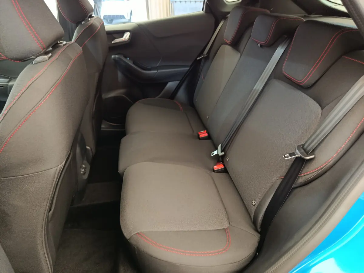 Vue côté droit de la banquette arrière noire avec surpiqûres rouges du Ford Puma bleu 2025 ST-LINE hybride.