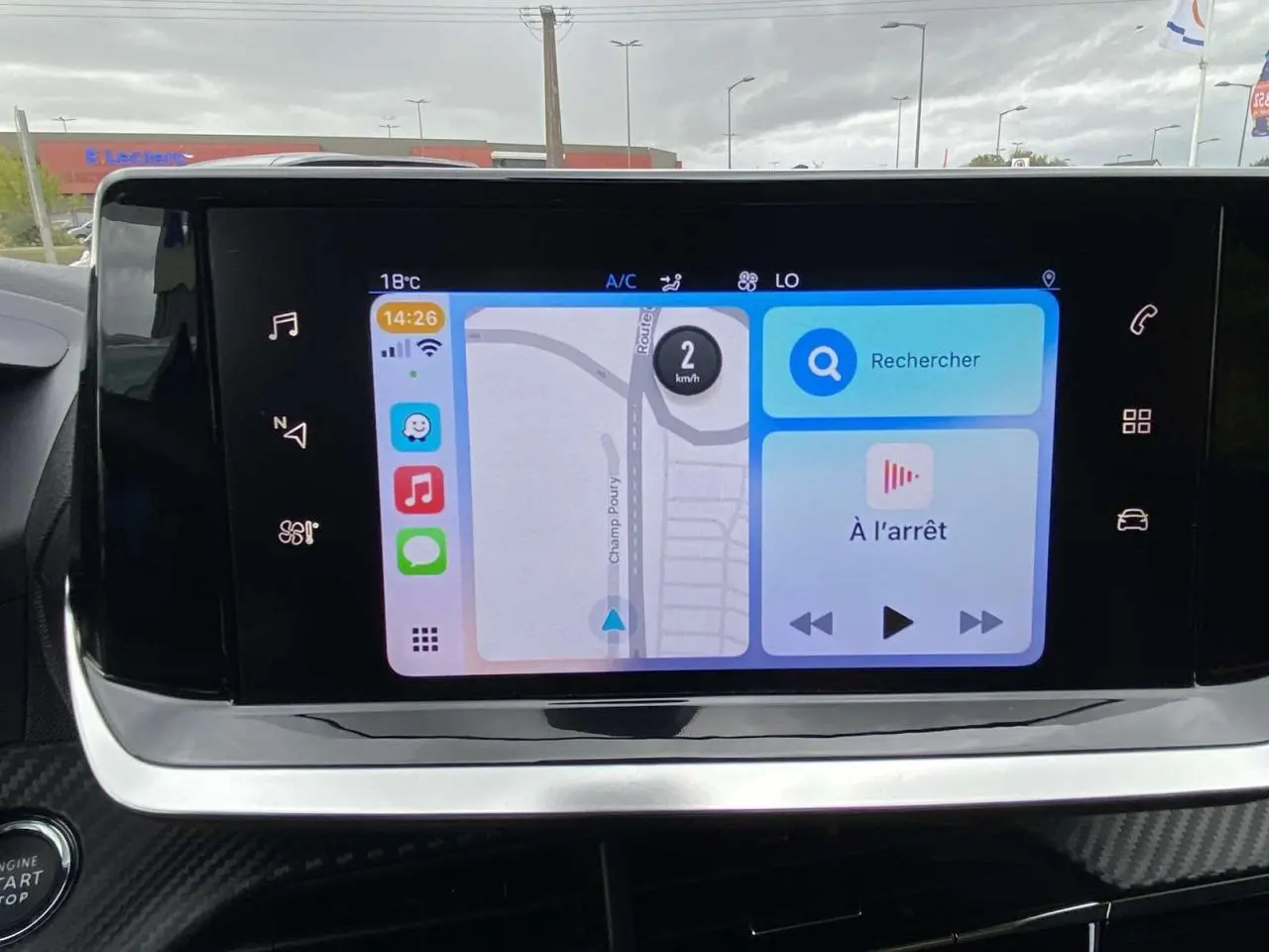 Écran tactile central affichant la navigation et commandes multimédia dans le Peugeot 208 bleu, vue intérieure frontale.