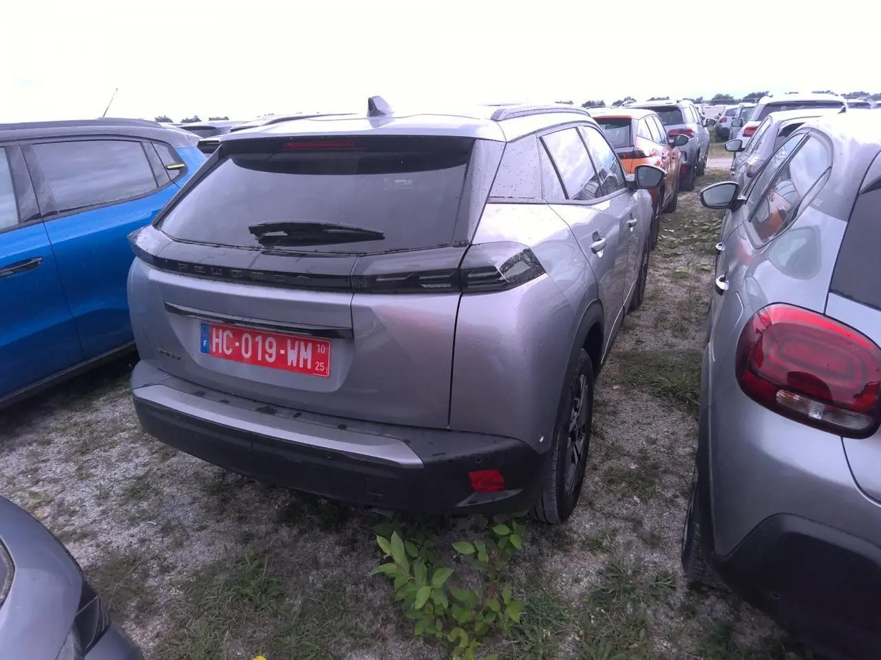 Vue 3/4 arrière d'un Peugeot 2008 gris clair avec toit noir et feux arrière LED en forme de griffes.