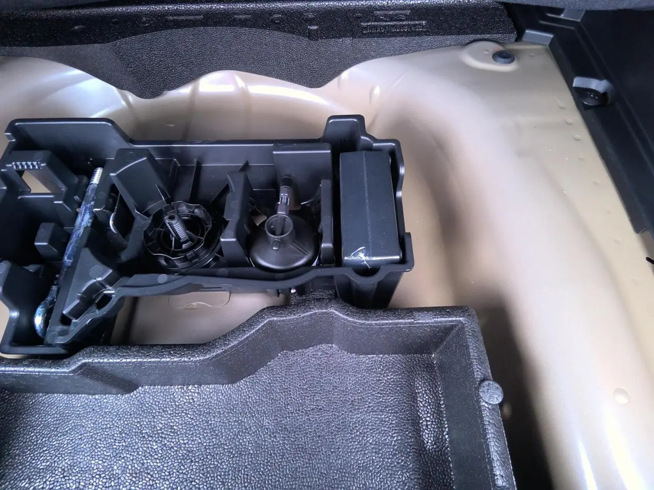 Vue rapprochée du coffre d’un Peugeot 2008 gris clair montrant le rangement pour outils et accessoires.