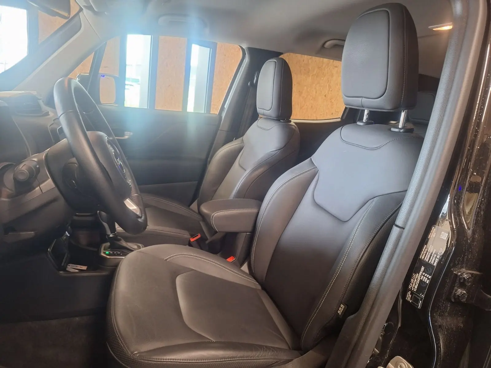 Vue intérieure côté gauche du Jeep Renegade 2024 noir, sièges avant en cuir noir avec coutures apparentes.