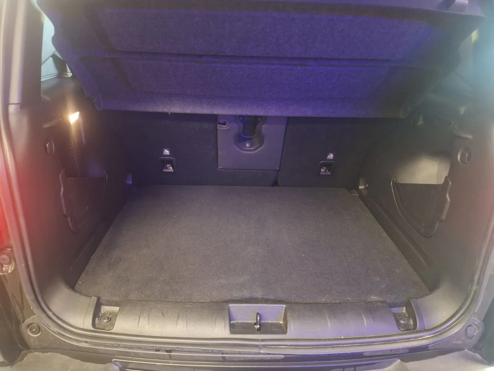 Coffre ouvert d'un Jeep Renegade noir 2024, montrant l'espace de chargement vide et l'éclairage intérieur.