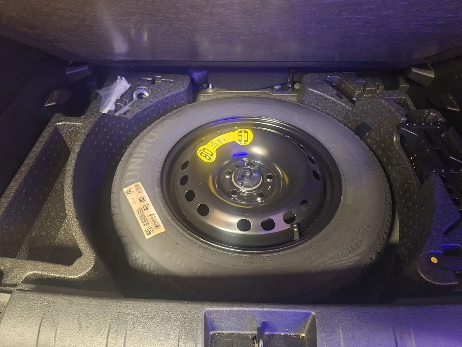 Vue plongeante sur la roue de secours noire dans le coffre du Jeep Renegade 2024 hybride noir.