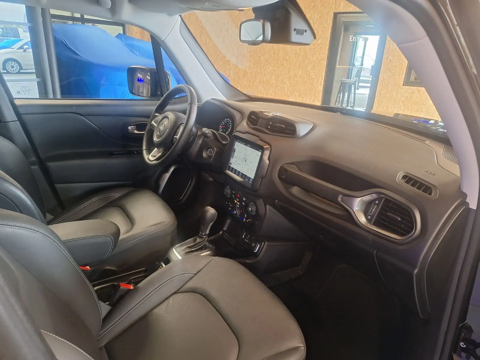 Intérieur noir cuir de la Jeep Renegade 2024, vue côté conducteur avec tableau de bord et écran tactile central.