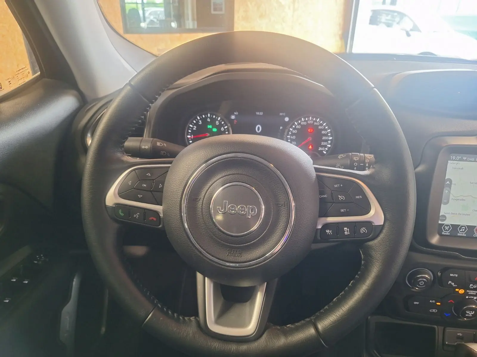 Vue centrée sur le volant noir en cuir du Jeep Renegade 2024, avec tableau de bord et écran tactile visibles à droite.