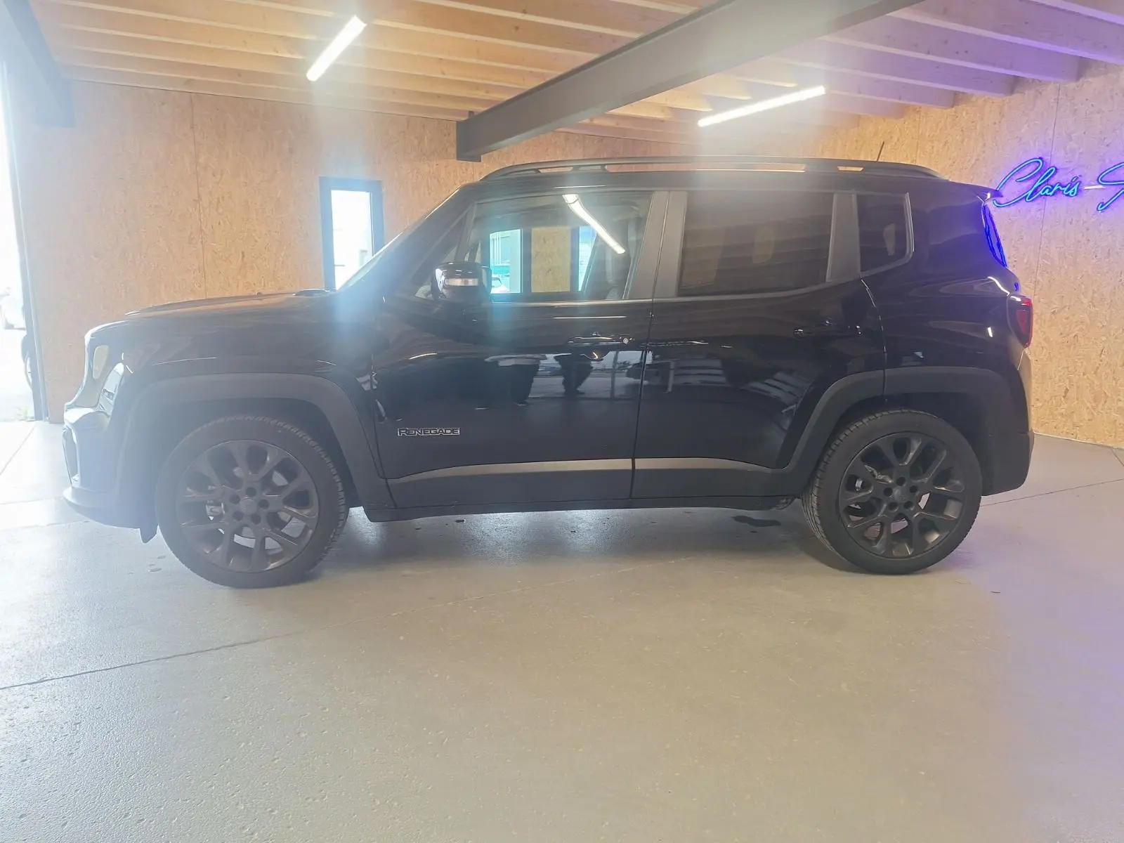 Jeep Renegade noir en vue profil côté gauche, avec jantes foncées et intérieur visible à travers les vitres.