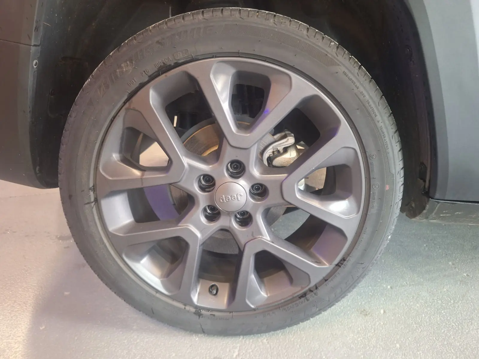 Gros plan sur la roue avant droite du Jeep Renegade noir 2024, mettant en valeur la jante alliage et le logo central Jeep.