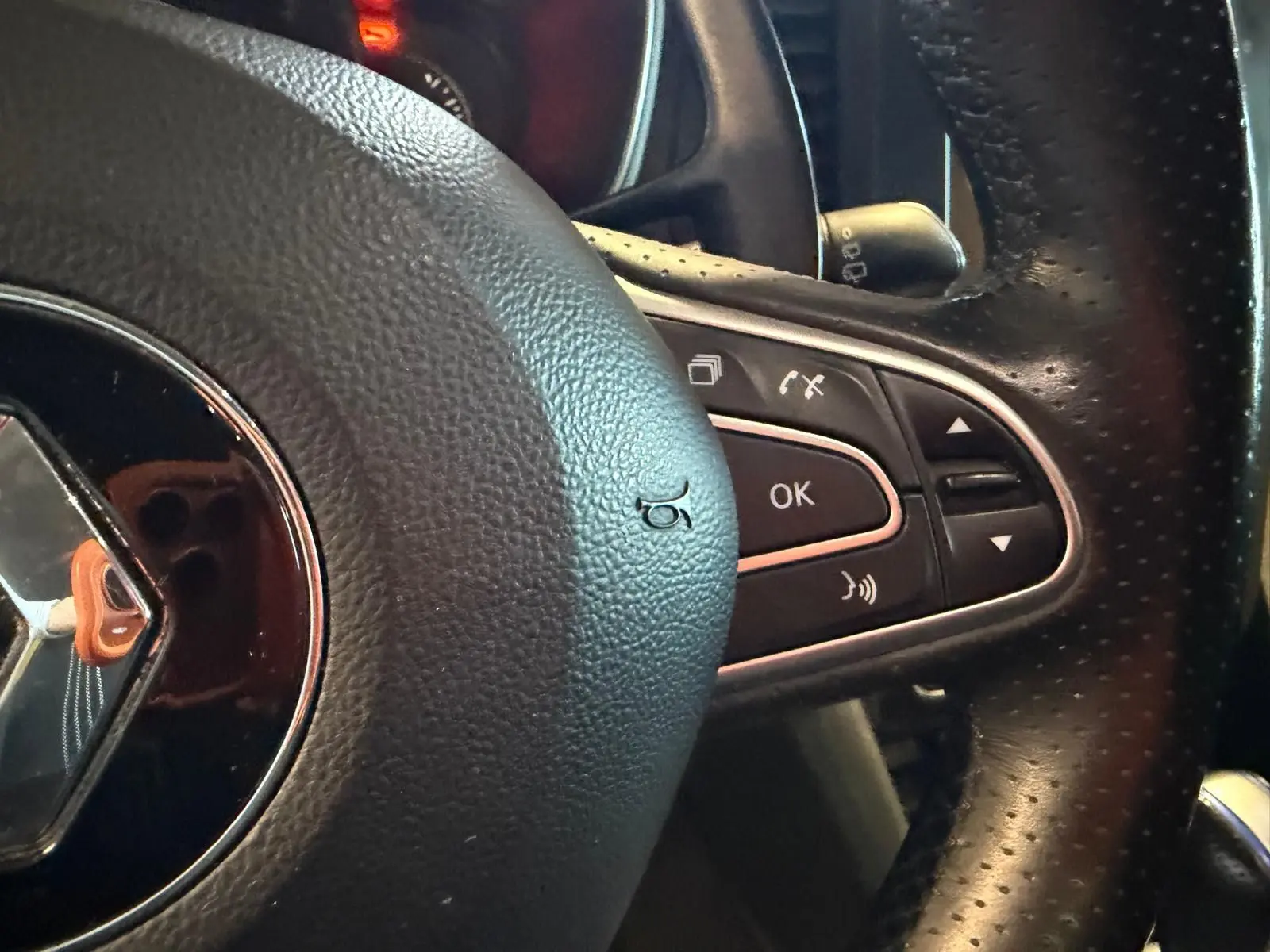 Gros plan sur le volant en cuir perforé noir de la Renault Mégane Break GT 2017, avec commandes intégrées côté droit.