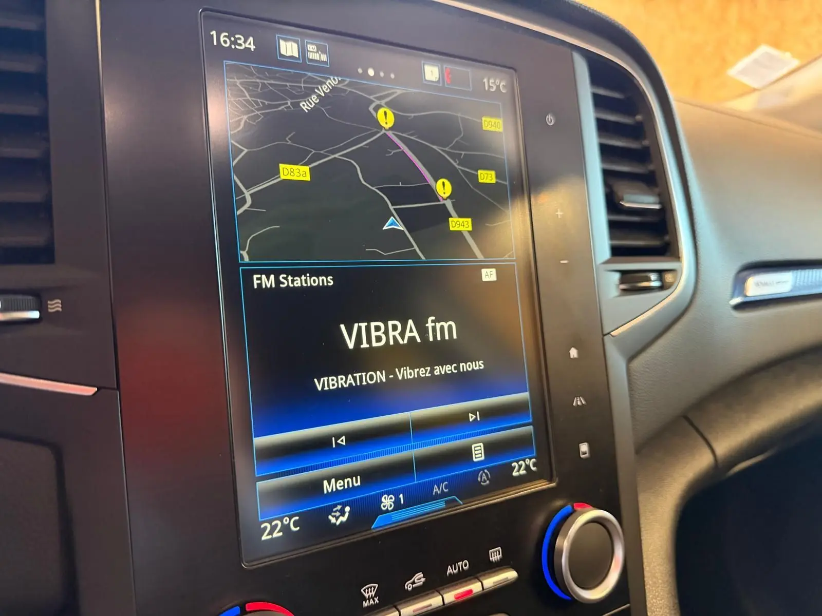 Vue rapprochée de l’écran tactile central du tableau de bord de la Renault Mégane Break GT 2017, affichant la navigation et la radio FM.