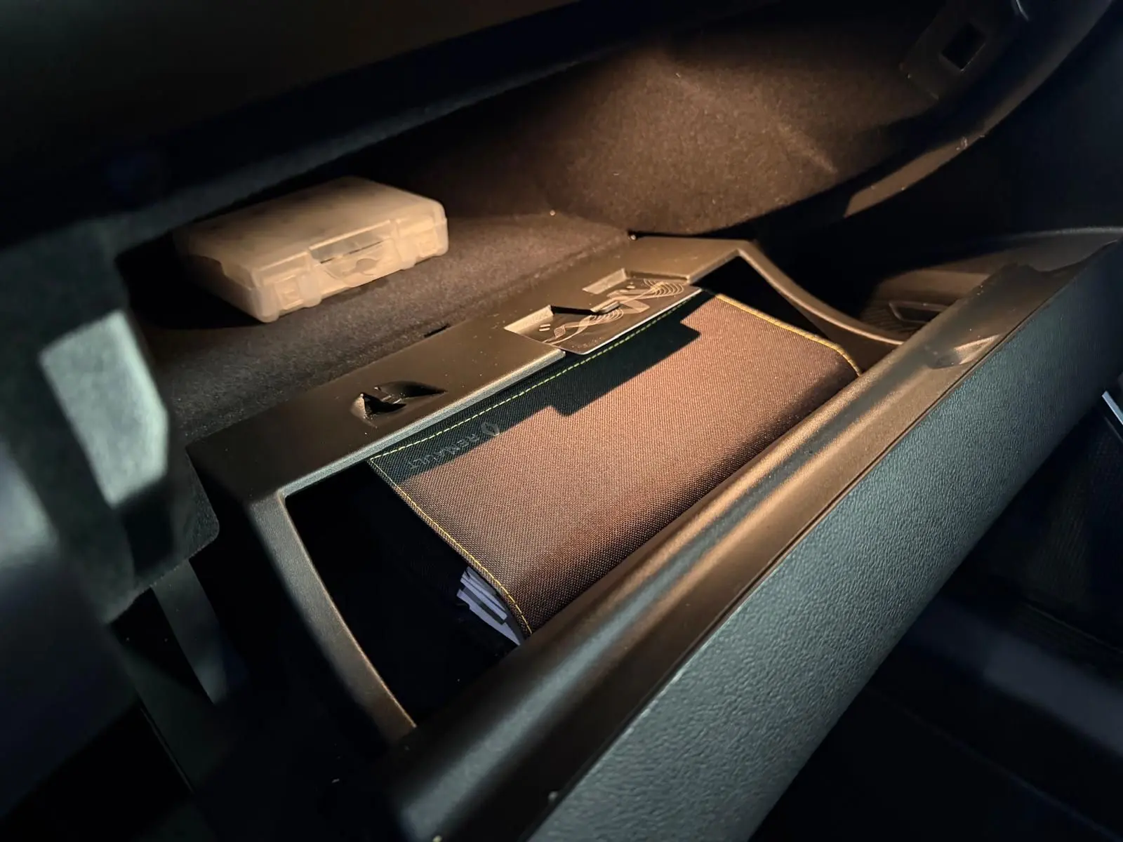 Vue rapprochée de la boîte à gants ouverte du Renault Mégane Break GT gris, avec un manuel de bord visible à l'intérieur.