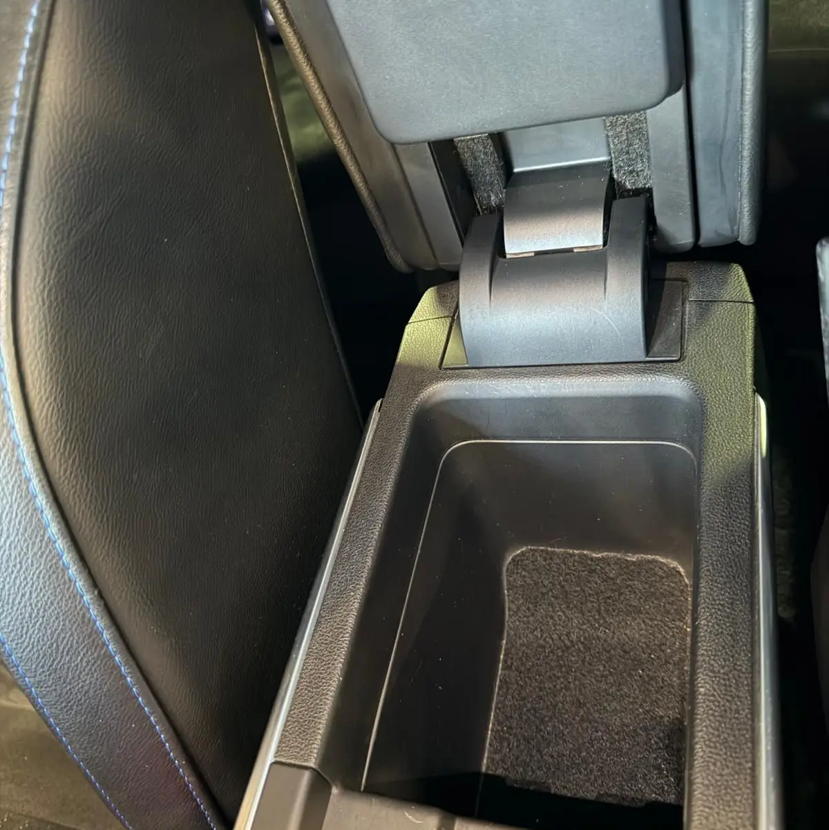 Vue rapprochée de l'accoudoir central ouvert avec rangement intérieur sur Renault Mégane Break gris, intérieur noir.