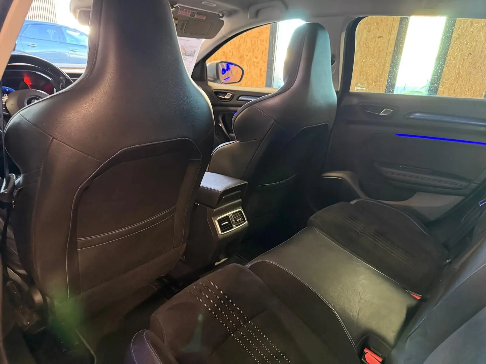 Vue intérieure arrière de la Renault Mégane Break GT 2017, sièges noirs en cuir et alcantara avec éclairage d'ambiance bleu sur la porte.