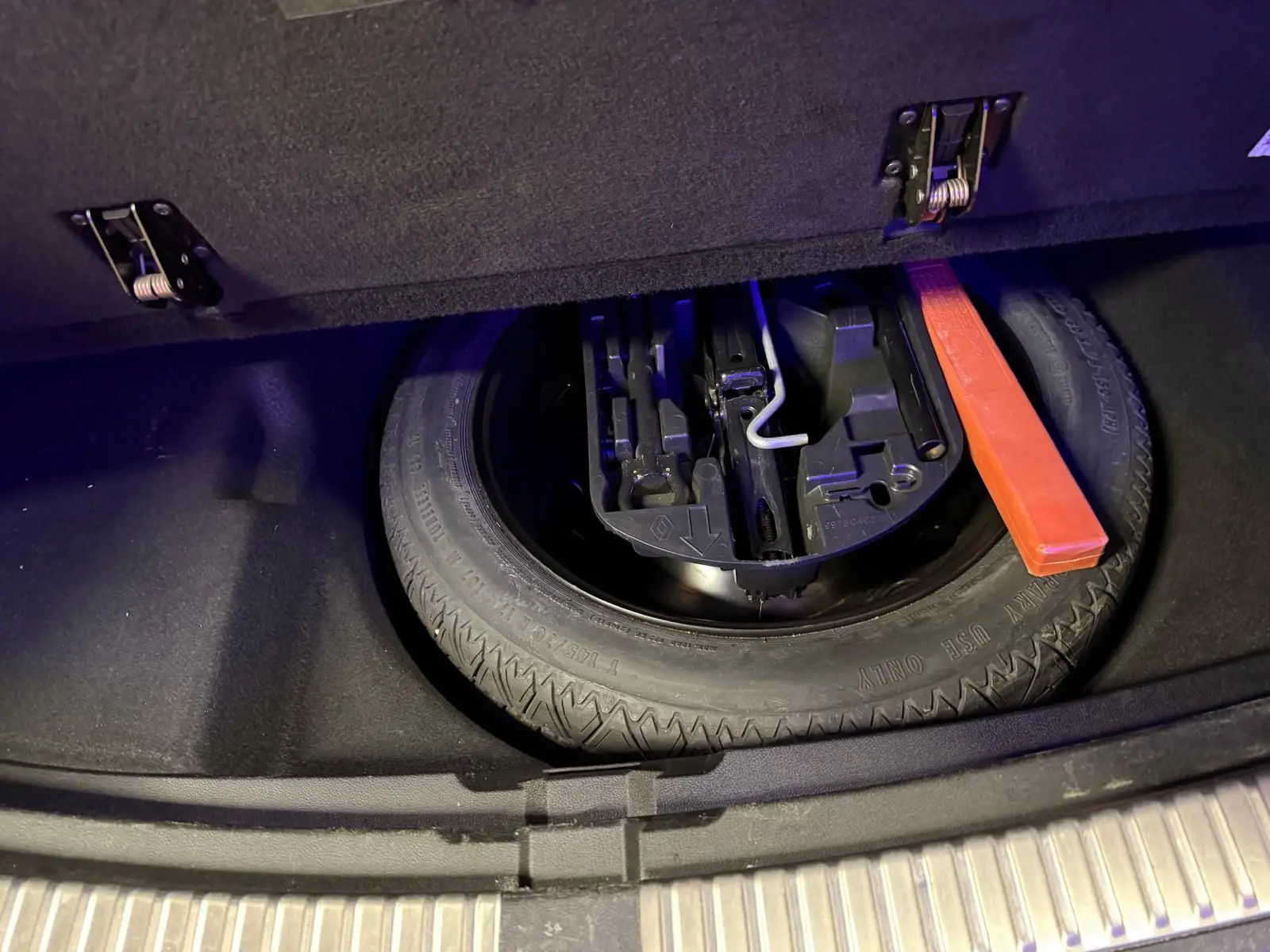 Vue plongeante sur la roue de secours et les outils de la Renault Mégane Break GT 1.6 DCI 165 EDC gris dans le coffre ouvert.