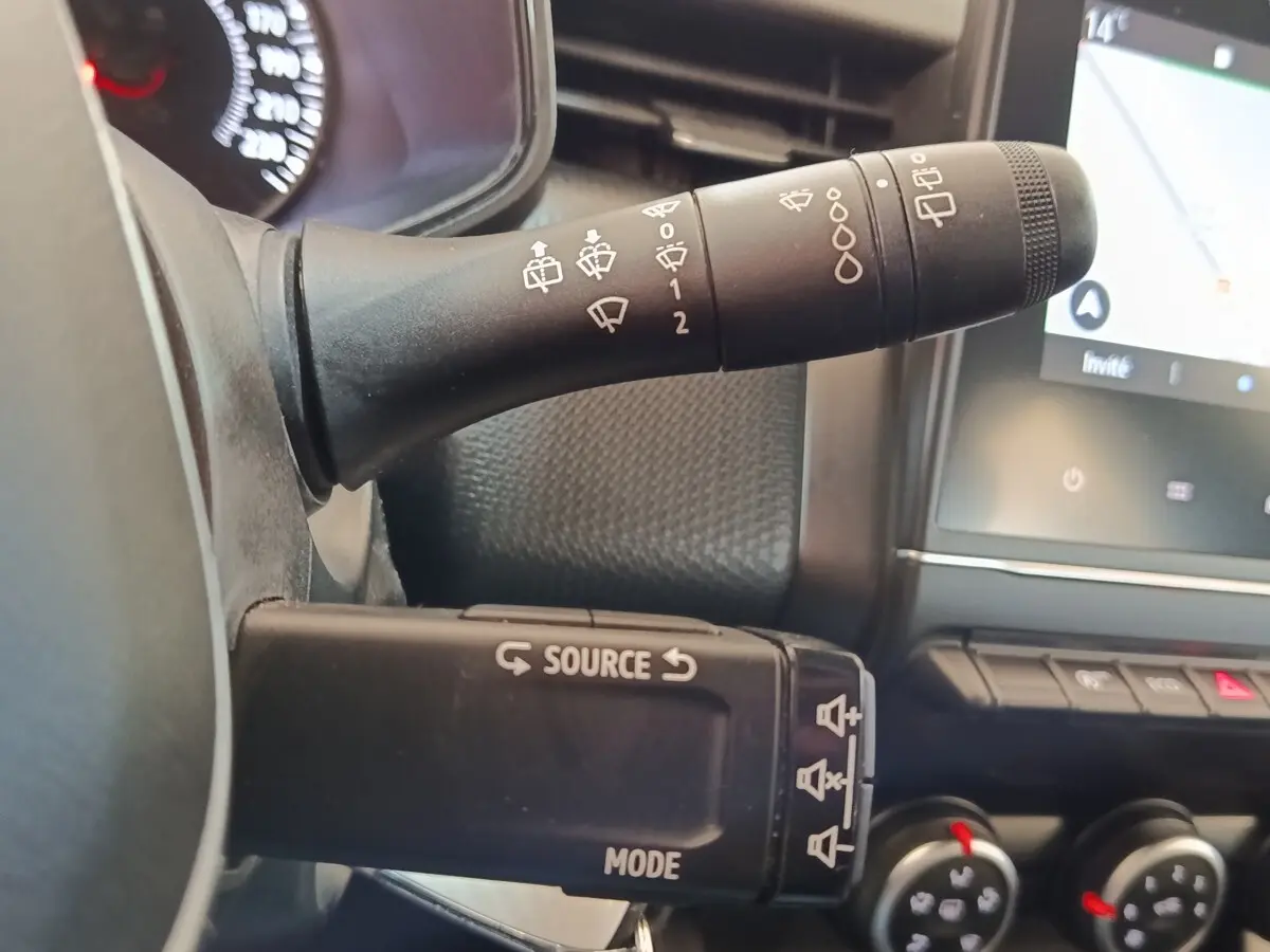 Gros plan sur les commandes au volant et le levier d'essuie-glace du tableau de bord d'une Renault Clio Business Blue dCi 100.