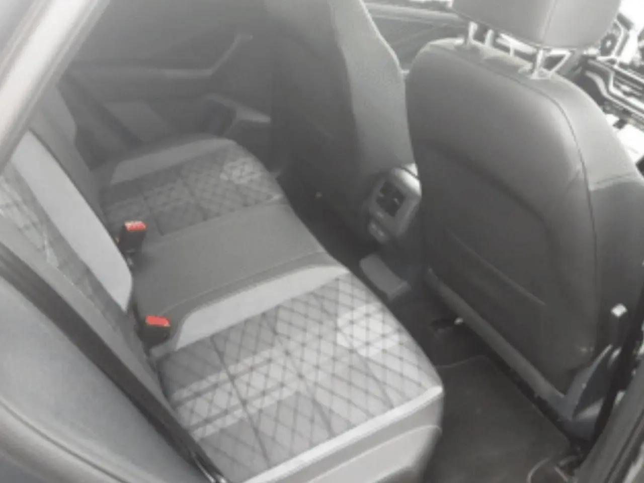 Vue intérieure arrière côté droit du Volkswagen T-Roc 2025, sièges tissu noir et gris avec surpiqûres croisées.