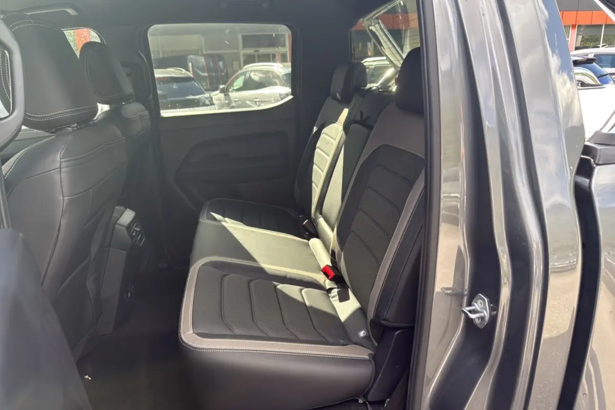 Vue latérale droite de l'intérieur arrière du Volkswagen Amarok Simple Cabine 2025 gris foncé avec sièges en cuir noir.