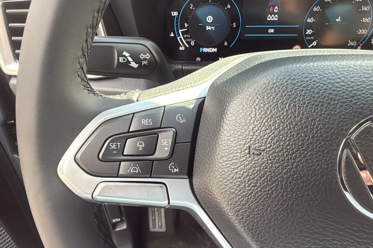Gros plan sur le volant cuir noir du Volkswagen Amarok 2025, avec commandes de régulateur de vitesse et tableau de bord numérique.